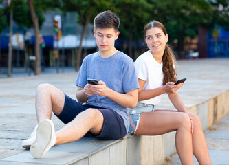 Fototapeta na wymiar Two young people with mobile phones are sitting on the step