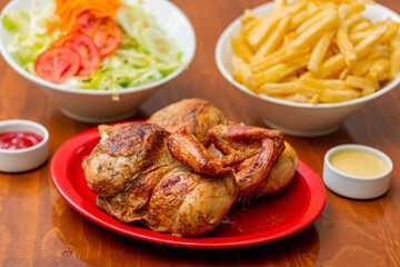 Grilled chicken with french fries on a wooden table.
