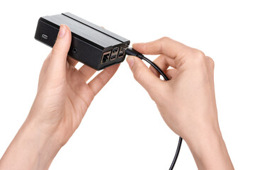 Female hands hold a metal mini computer or black media player and insert a usb cable with a connector. Isolated on white background.