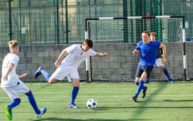 Football soccer players with ball. Footballers kicking football match on the pitch. Young teen soccer game