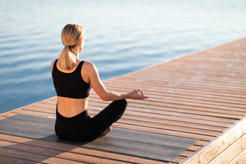 Fototapeta na wymiar Morning Meditation. Calm Blond Woman Practicing Yoga Outdoors, Meditating In Lotus Position
