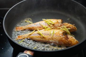 frying fishes by a pan