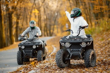 Man and woman driving quad bike in autumn forest