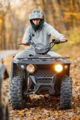 Young man driving quad bike in autumn forest