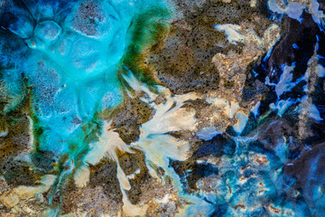 Abstract background that has the appearance of being an aerial image over a rock coast with brilliant blue water.
