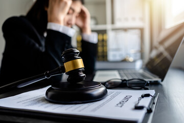 Law firm office, Selective focus judges gavel with businesswoman or female lawyer having a headache in the background,.scales of justice, document legal, justice advice service concept.