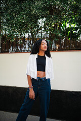 Portrait of carefree african teenager posing in the city street. She is wearing jeans.