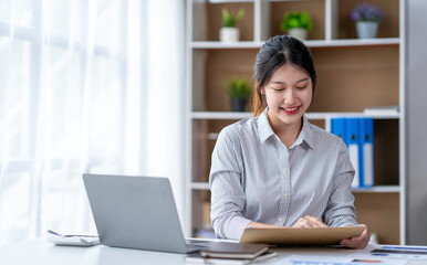 Young woman working on a laptop in the office. Asian businesswoman sitting at her workplace in the office.  Beautiful Freelancer Woman working online at her home.