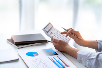 crop shot of business woman checks her work and uses a calculator to calculate her annual financial statements. Turnover and Profit Balance Sheet Making financial records in paper audits.