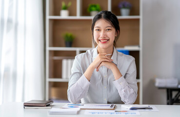 asian businesswoman smiling and look at camera while working on laptop at modern office. Woman...