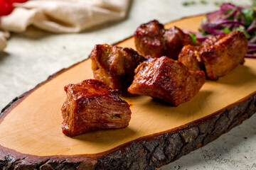 Kebab of pork with red onion on the board on stone table macro close up