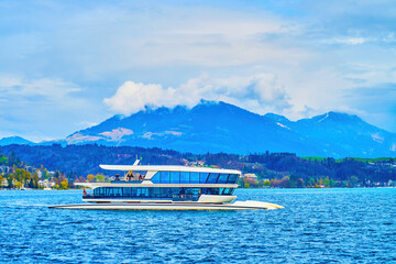 Modern catamaran sails along the Bay of Lucerne on lake Lucerne in surrounding of Alps mountains,...