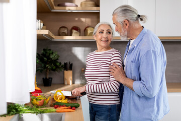Portrait Of Happy Senior Spouses Cooking Healthy Food Together In Kitchen