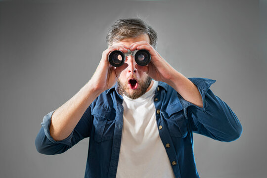 a young man looks through binoculars portrait