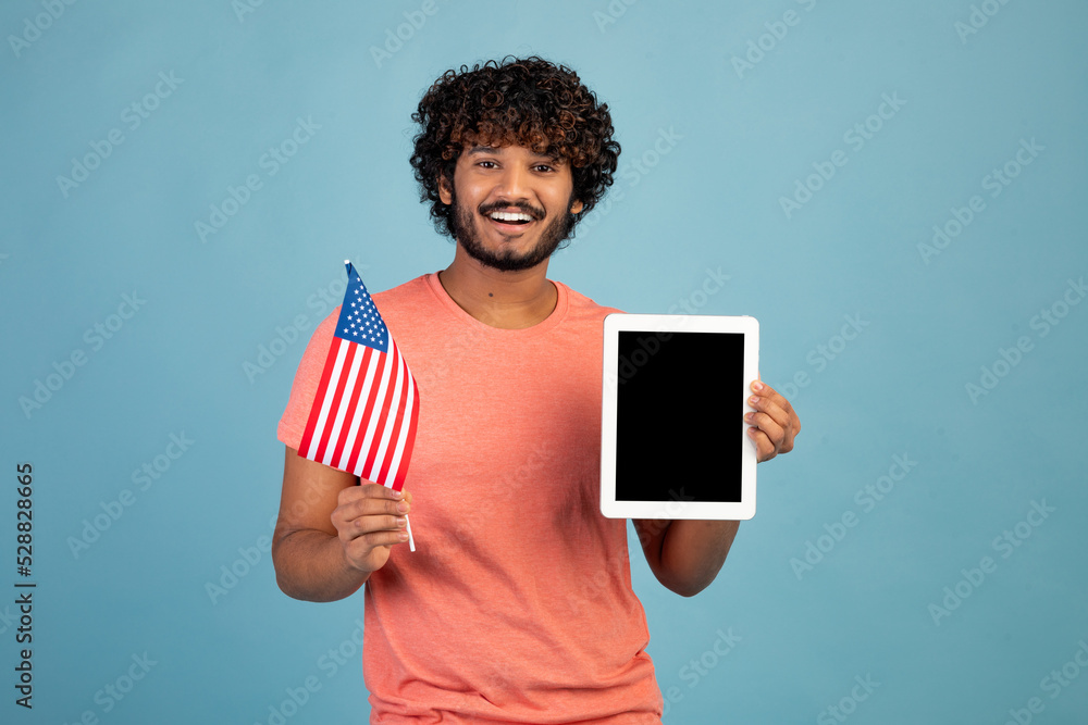 Wall mural Positive eastern student showing American flag and digital tablet, mockup