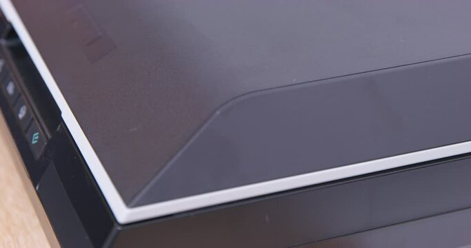 Dog paw puts sheet in scanner closes lid makes copy close-up. Black multifunction printer, MFP. Assistant copies documents joke. Small home scanner, copier, easy to use device. Groomed pet claws