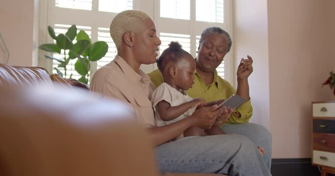 Multi-Generation Family using Digital Tablet in Living room on Sofa