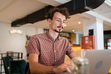 One young adult caucasian man work remote from cafe on laptop computer