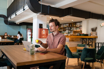One young adult caucasian man work remote from cafe on laptop computer