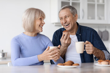 Happy elderly spouses drinking tea with pastry at home