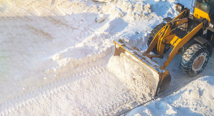 A large orange tractor removes snow from the road and clears the sidewalk. Cleaning and clearing...