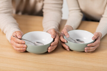 Male and female hands with empty bowls, closeup