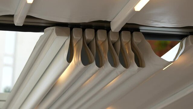 4k video, the move of a retractable awning of roof for protect from sun in garden at home or in terrace at a restaurant. 