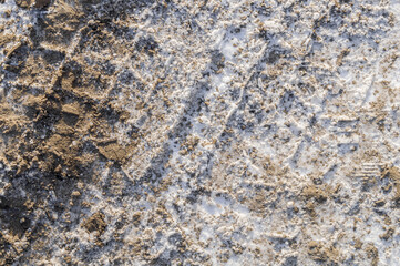 Traces of truck tires on a dirt road covered with mud and melted snow. Selective focus