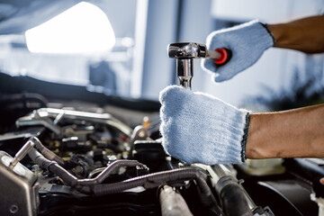 Obraz premium close up of view Auto mechanic repairman using a socket wrench working engine repair in the garage, change spare part, check the mileage of the car, checking and maintenance service concept.