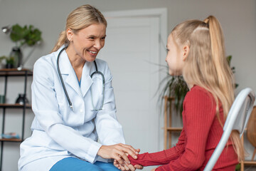 Pretty schoolgirl having appointment with friendly professional female pediatrician at modern clinic, copy space