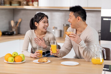 positive japanese spouses having fun while eating at kitchen