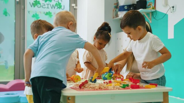 Sensory Play At Nursery School. Toddlers With Their Teacher Having Fun With White, Fluffy Cloud Dough, And Using Modeling Tools Such As Colorful And Textured Rolling Pins, Cutters, Silicone Shape