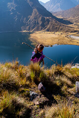 portrait of a latin woman, climbing a hill, with a lake in the background