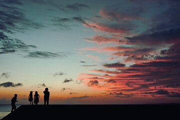 silhouette of a family near the ocean at sunset