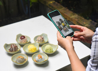 A woman taking picture of many ice cream on white table