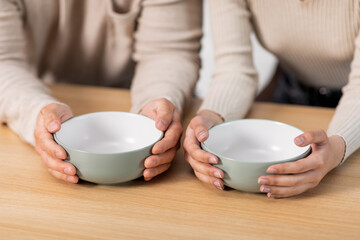 Unrecognizable people sitting at table with empty bowls