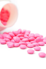 Obraz na płótnie Canvas pink round pills or tablets scattered on white background from its bottle or container, medical drugs taken soft-focus with copy space