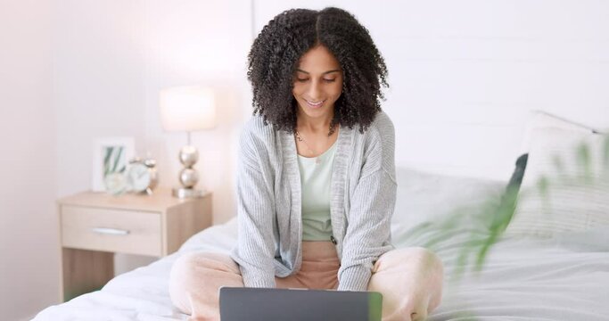 Woman blog writer typing with laptop for internet website and reading funny social media post on bed in home. Freelance worker in bedroom working remote while writing funny or comic web content