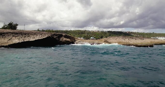 Aerial view low over waves hitting a cliff, revealing the Jobos beach in Puerto Rico, USA - rising, drone shot
