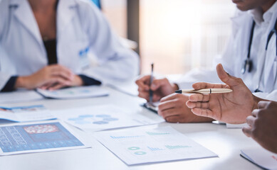Team, medical analysts and doctors consulting with paperwork of graphs, data and charts in hospital...