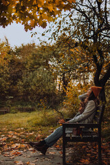 Young woman sitting on bench alone and looking up in fall season