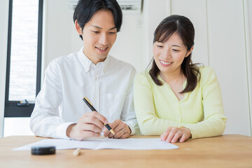 Obraz premium 婚姻届けにサインをする日本人夫婦