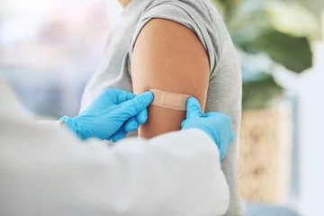 Fotobehang Covid virus vaccination, vaccine and doctor hands with plaster on patient arm in a medical hospital or clinic. Healthcare worker help, trust and safety flu shot antigen for protection against disease © Azeemud-Deen Jacobs/peopleimages.com