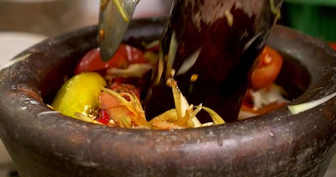 Close-up front view, chef cooking making mix ingredients chili garlic tomato for spicy green papaya salad or Som Tum, Thai traditional street food.