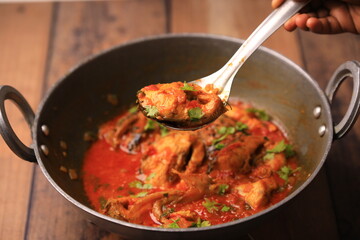 Indian desi style fish curry cooked in a traditional pot closeup with selective focus and blur