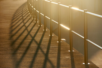 metal handrail casting harsh shadows on concrete walkway - 528840015