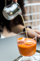 Stainless steel teapot pouring tea on tea ice cubes