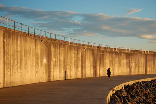 lonely walker at sunrise on concrete walkway