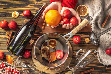 Ingredients for mulled wine, mugs, saucepan on a wooden table, top view. Concept of cooking a...