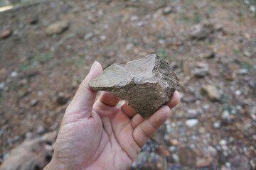 Hand holding a raw shale stone rock. sedimentary rock.